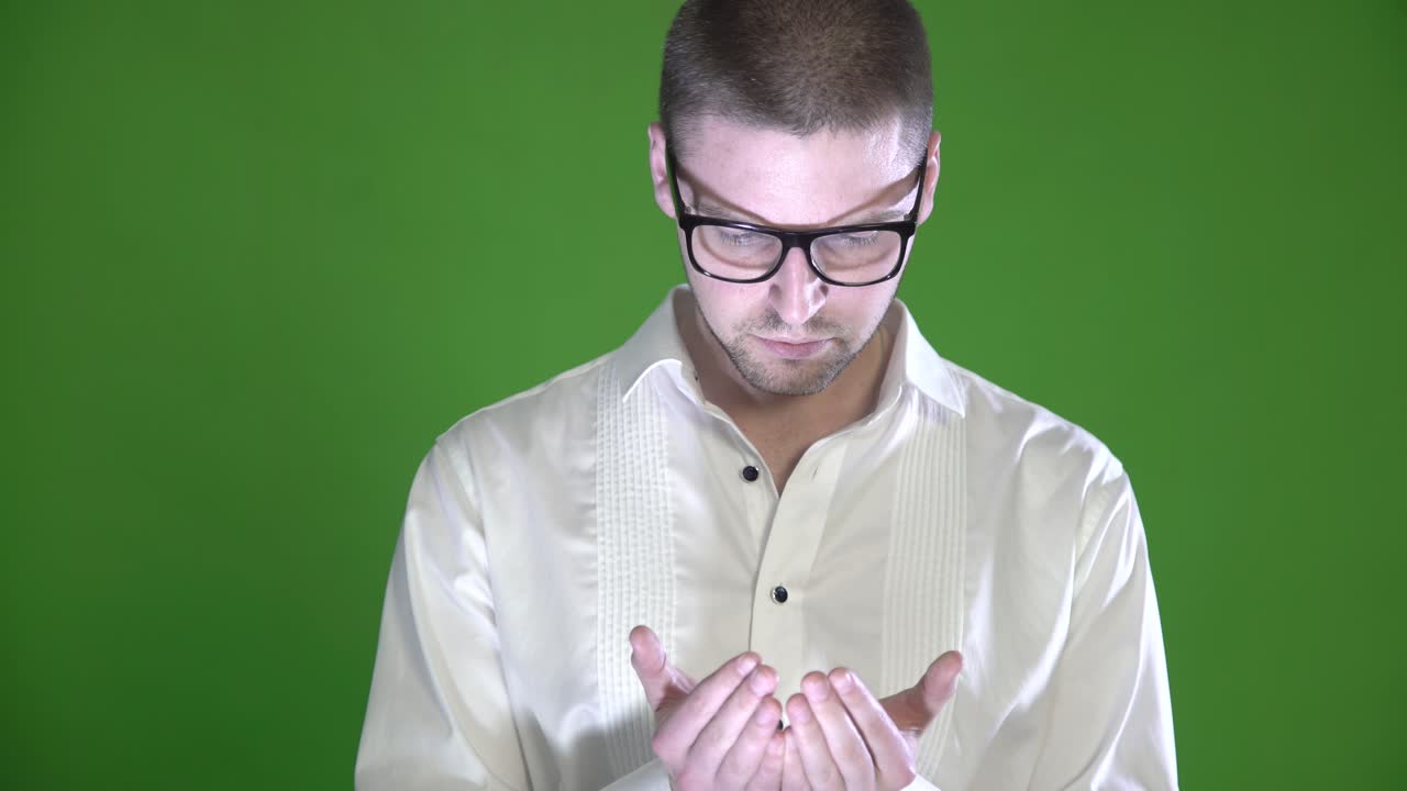 질과 안경을 가진 질감 있는 남자가 초록색 배경에서 손바닥을 조사합니다.