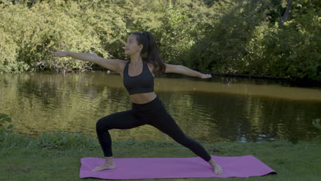 mujer joven haciendo ejercicios de yoga de pose de guerrero cerca del estanque