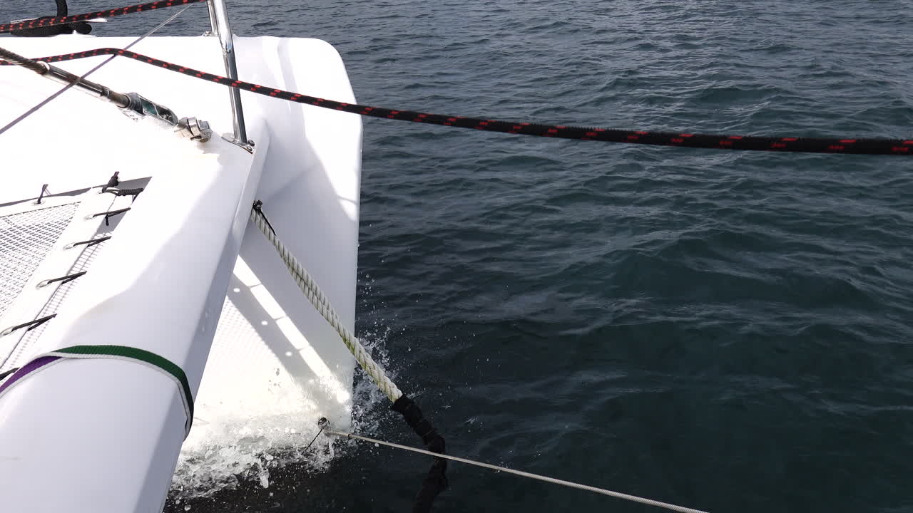 Close up shot of the Bow of a Catamaran cutting through the water on a sunny day