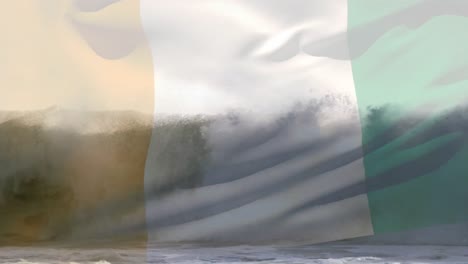 digital composition of waving ivory coast flag against waves in the sea