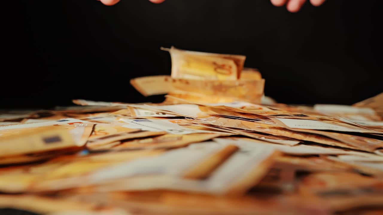 Outstretched fingers desperately attempt to gather euro bills from ground