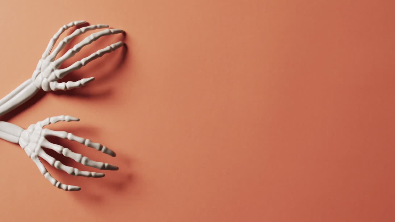 video de las manos del esqueleto de halloween con espacio de copia en fondo naranja