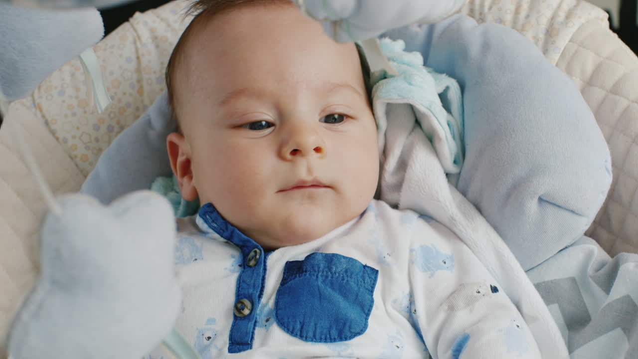 Il piccolo di due mesi è nella culla. Non dorme. Primo piano sorridente.