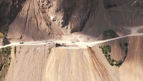 Bird's-eye-view-of-heavy-machinery-carrying-and-dumping-waste-to-clear-the-road-at-a-limestone-mine-in-Jujuy-Province,-Argentina