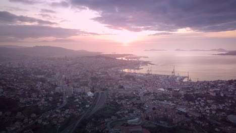 beautiful aerial sunset view over industrial cityscape at the atlantic coast in galicia with the cies island in the background. drone stablishing shot in vigo city.
