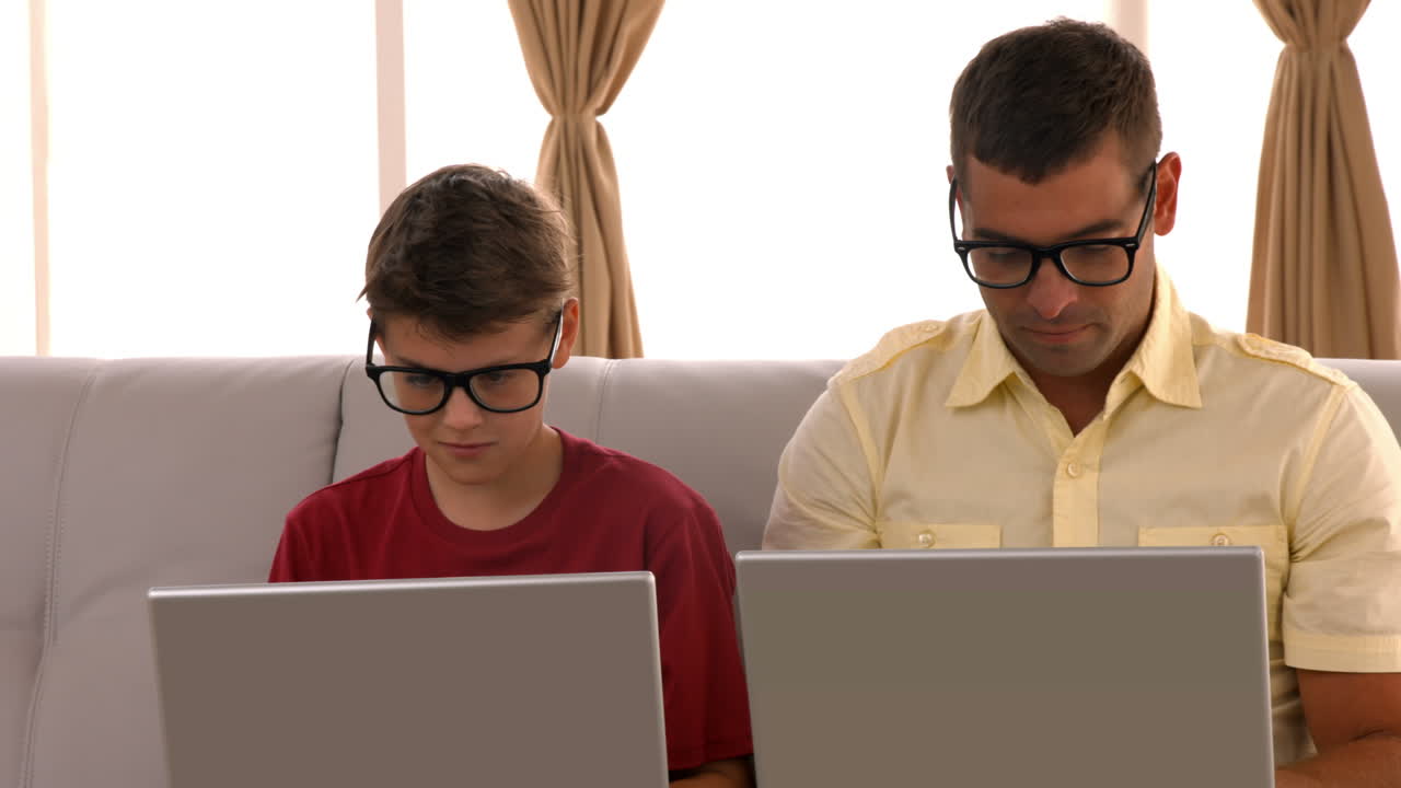 padre e hijo usando la computadora portátil en el sofá