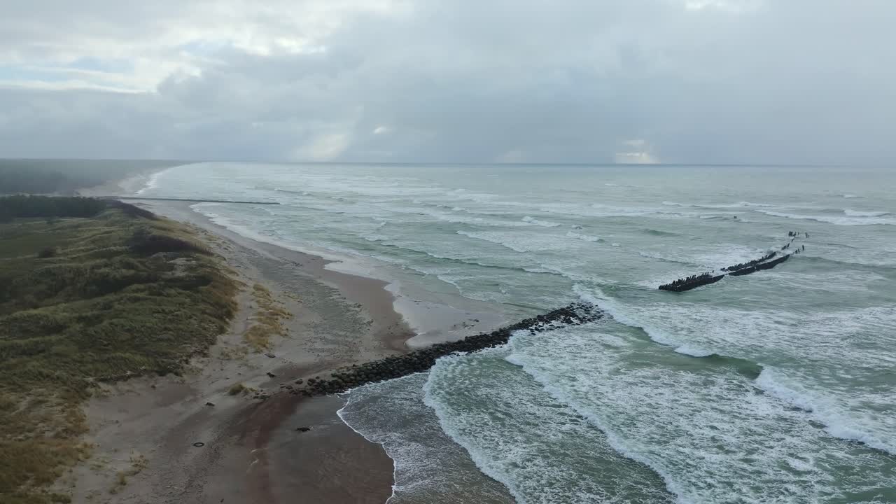 Serene aerial view of Pape, Latvia, windy beach with jetty and crashing waves