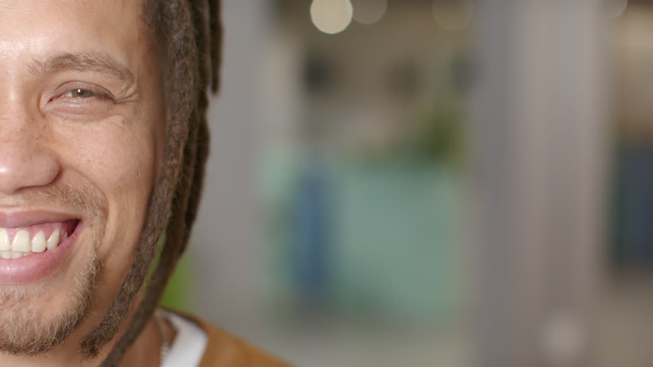Adult African American man seeing camera, smiling, squinting in studio with bokeh light, copy space