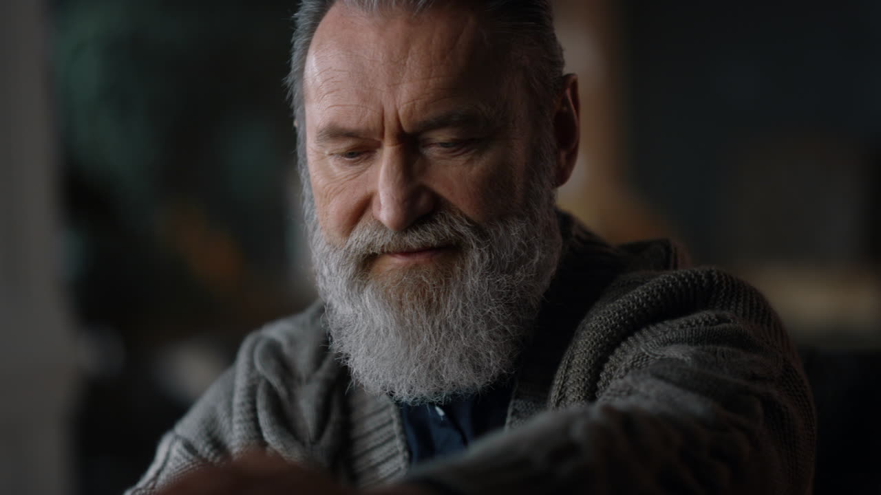 실내에서 노인 남자가 노트북을 열고 있습니다.