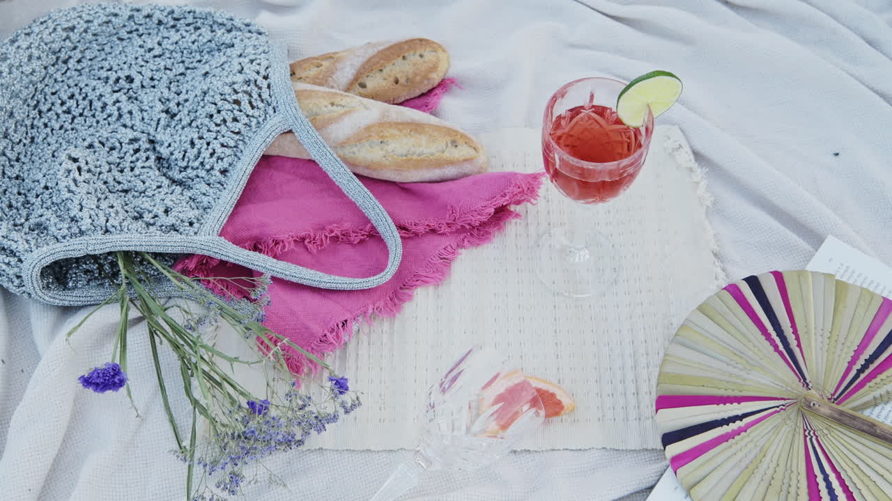 Getting A Glass Of Red Cocktail Drink From The Flat Lay With Pieces Of Baguette at a Luxury Picnic - close up