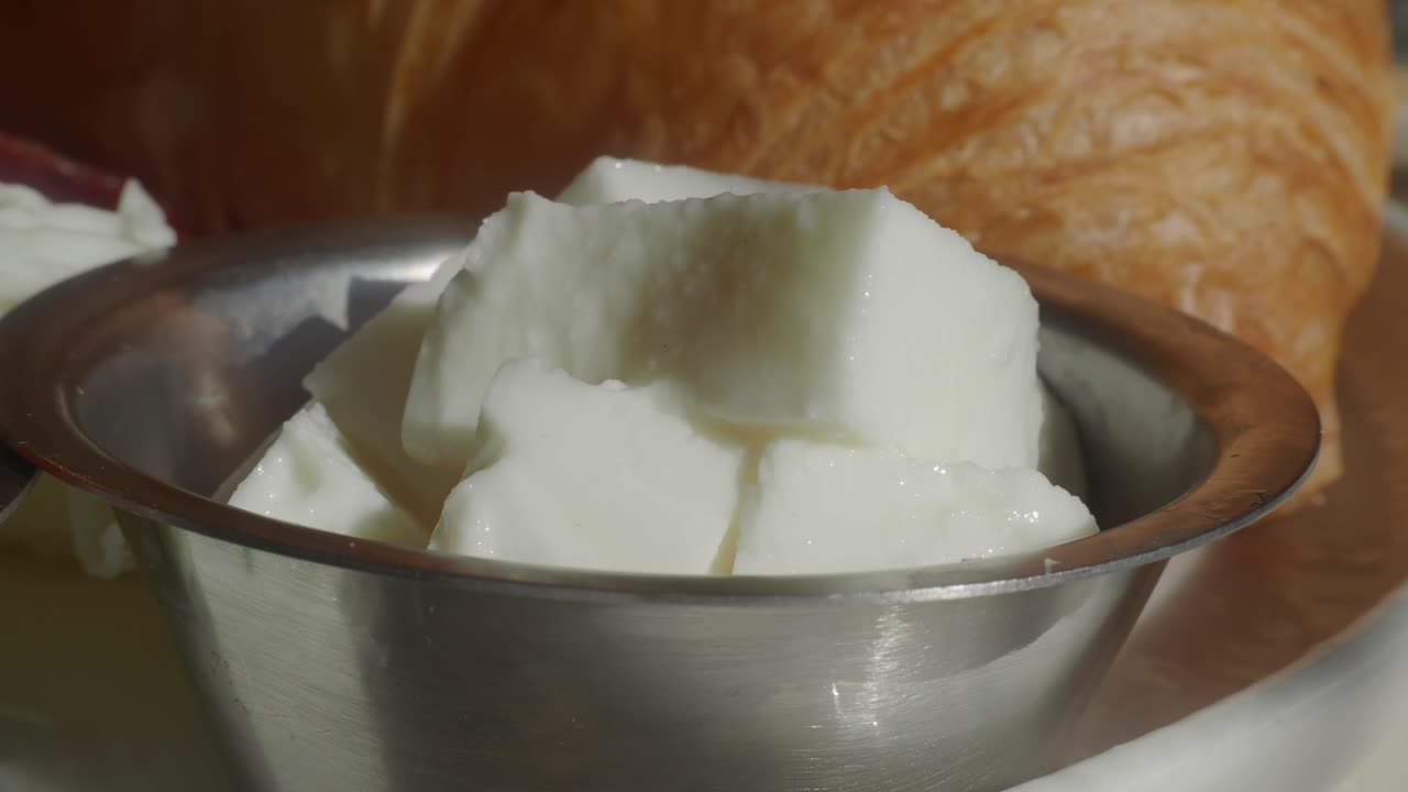 Kahvaltı masasında beyaz peynir küpleri ve kruvasan yakın çekim.