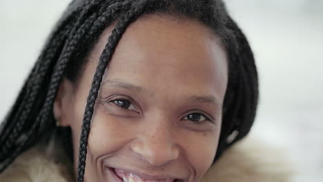 afroamericana joven feliz con trenzas en chaqueta gris con capucha de piel sentada afuera