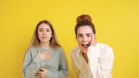 young women sharing laughter and happiness on yellow background
