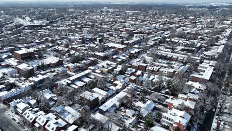 Aerial-view-of-a-sprawling-urban-area-covered-in-snow,-showcasing-a-vast-network-of-streets,-houses,-and-buildings-under-a-clear-winter-sky-in-the-USA