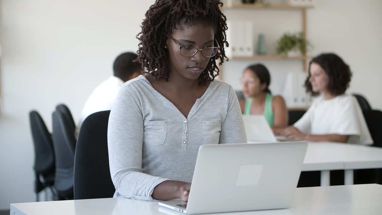 Focused African American woman using laptop at office.