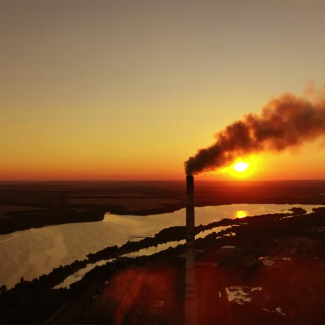 smoke from industrial pipe against the sunset. factory near the river on the setting sun. pollution the atmosphere.