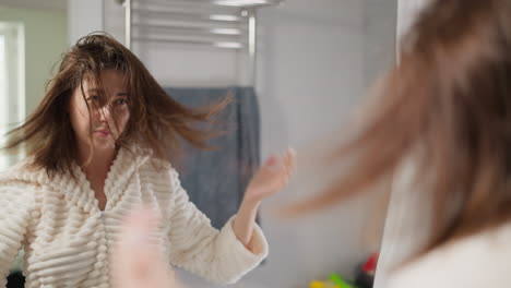 attractive lady rubs hair with nourishing oil in bathroom. woman does care treatments for scalp with shiny hair in bright bathroom slow motion