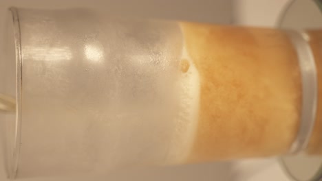 toma vertical de remolacha giratoria llena de cerveza dorada fría en el restaurante, primer plano