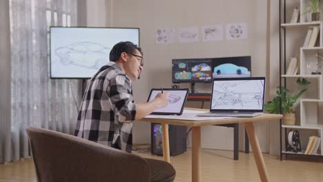 side view of asian male having a backache while drawing new car design concept on a tablet in the studio with tv and computers display 3d electric car model