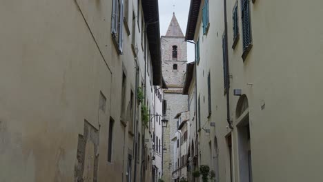 attractive bell tower seen from the middle of an alley at arezzo in tuscany, italy