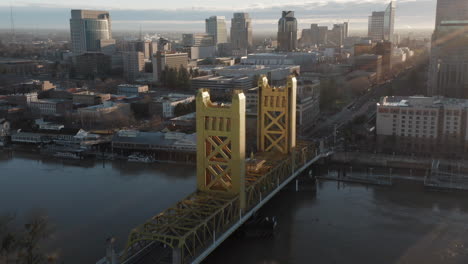 Aerial-drone-left-parallax-of-Tower-Bridge-and-Downtown-Sacramento,-CA,-including-Old-Sacramento---State-Capitol-in-background-during-sunrise