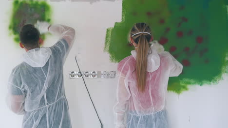 family in protective suits paints wall with bright sprays