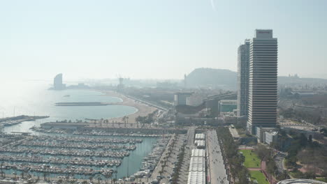 Descending-footage-of-port.-Rows-of-yachts-and-sailboats-moored-at-piers.-Panoramic-aerial-view-of-sea-coast-in-city.-Barcelona,-Spain
