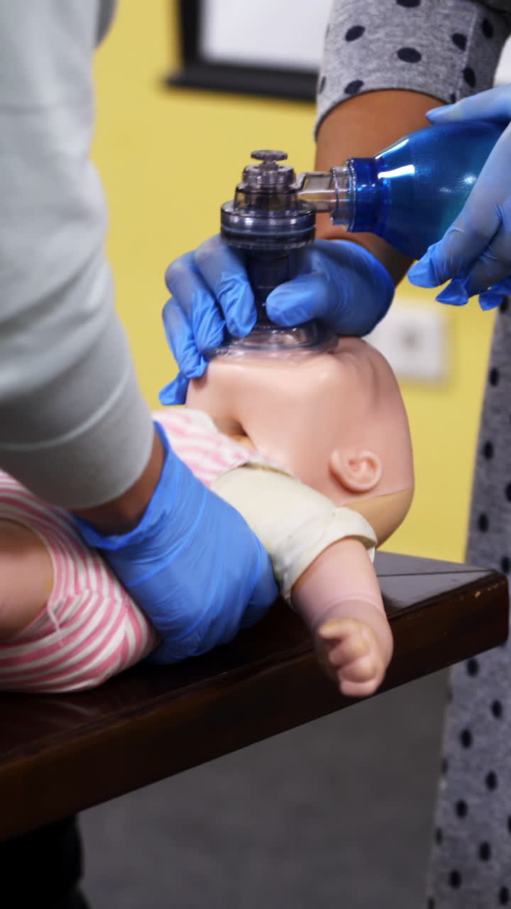 Medical mannequin doll for emergency aid. Training for giving first aid to a toddler. Breathing apparatus in woman's hands on a dummy of a child. Vertical video