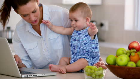 Bonita-Madre-Usando-Laptop-Y-Jugando-Con-El-Bebé.