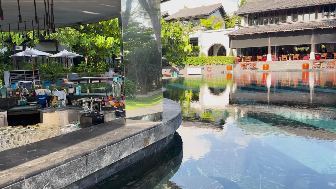 A tranquil luxury resort in Phuket with a reflective pool, lush greenery, and modern architecture under bright daylight