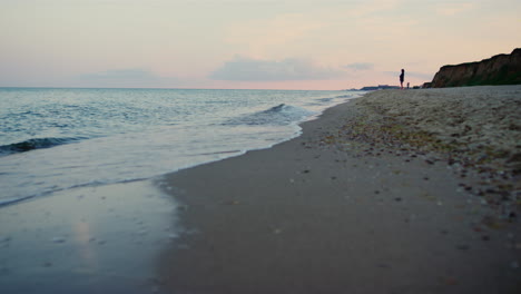 Water-waves-splashing-sea-beach.-Woman-silhouette-walking-sandy-beach-seashore