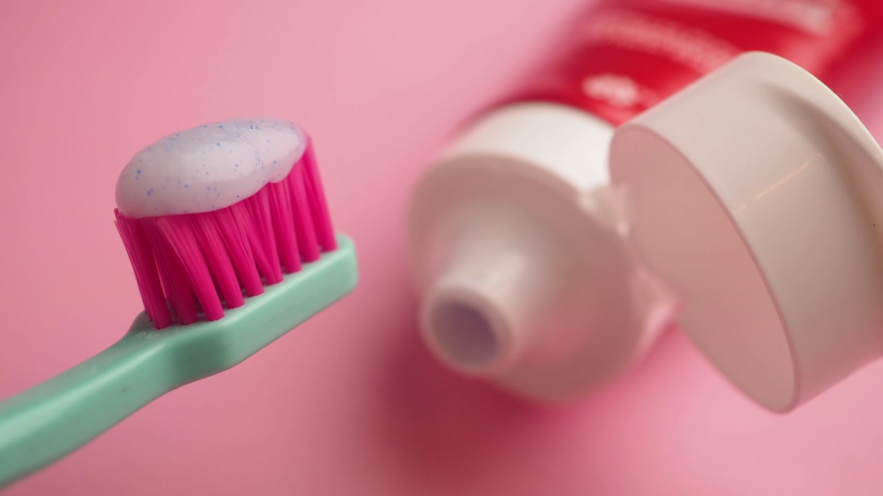 Toothbrush with Toothpaste and Tube on Pink Background