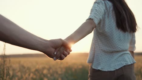 couple walking hand-in-hand at sunset