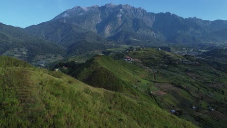 Hermosa-Toma-De-Drones-De-Los-Campos-De-Kundasnag-Que-Muestra-El-Monte-Kinabalu-Al-Fondo,-Sabah-Malasia,-A-La-Luz-Del-Día