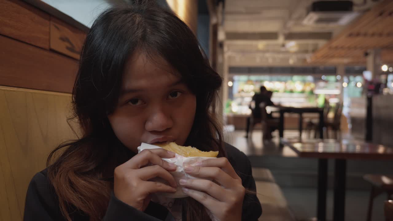 Asian girl enjoying a snack and showing it off to camera