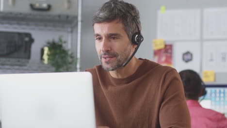 businessman wearing telephone headset talking to client in customer services call centre