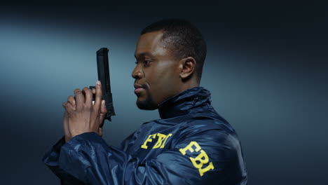 portrait shot of the young fbi policeman turning to the camera and pointing a gun at the camera