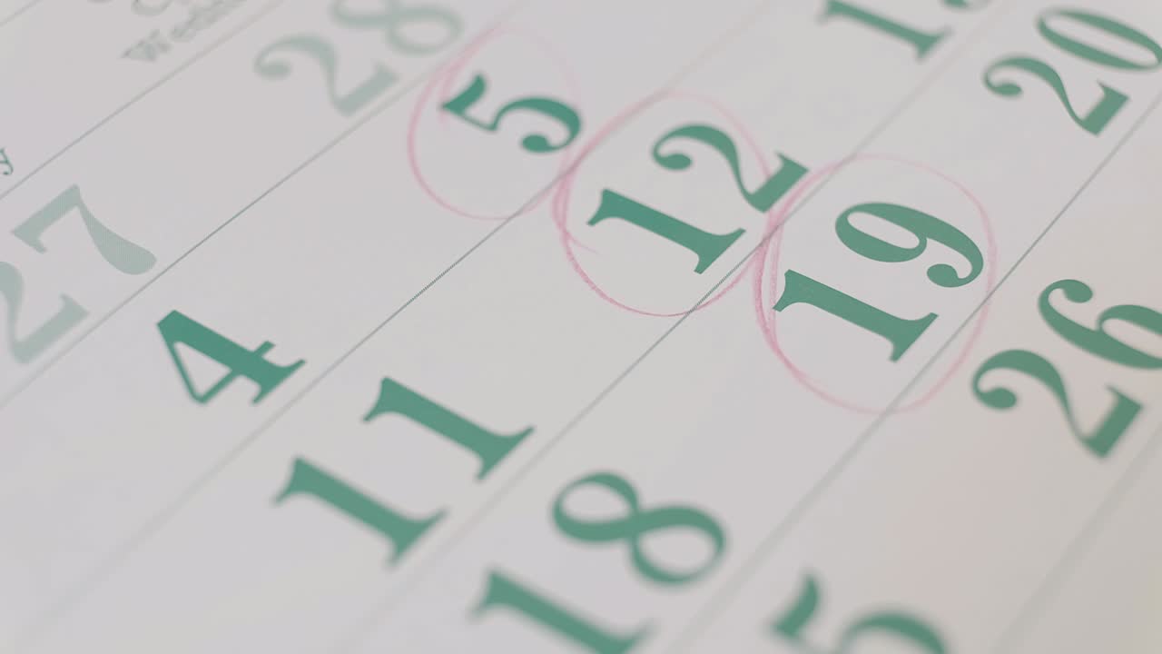 persona marcando fechas importantes en el calendario con un lápiz rojo.