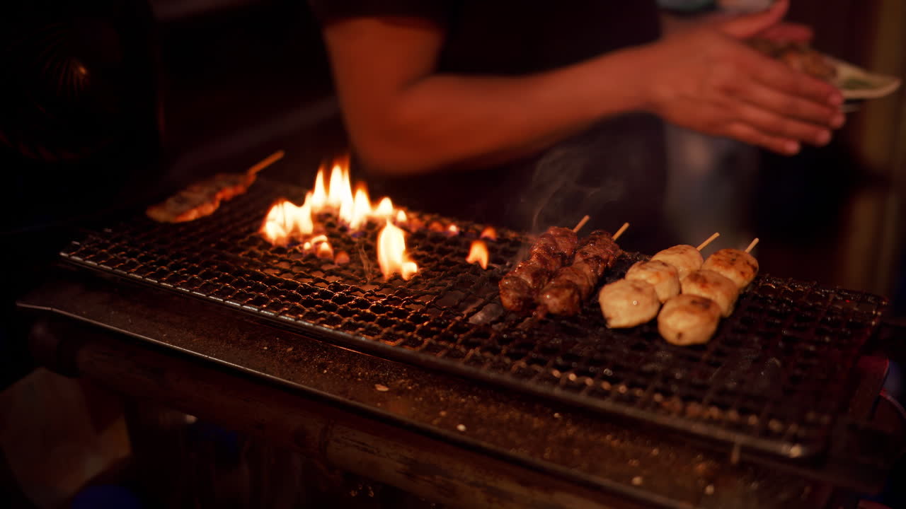 Close up of a chef cooking meat skewers on a grill at a Japanese restaurant