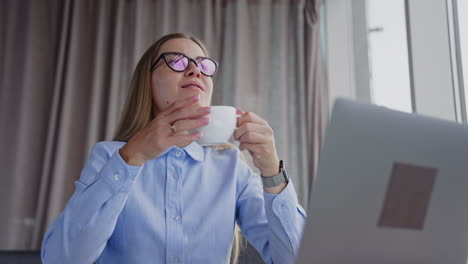 woman working at laptop and drinking coffee