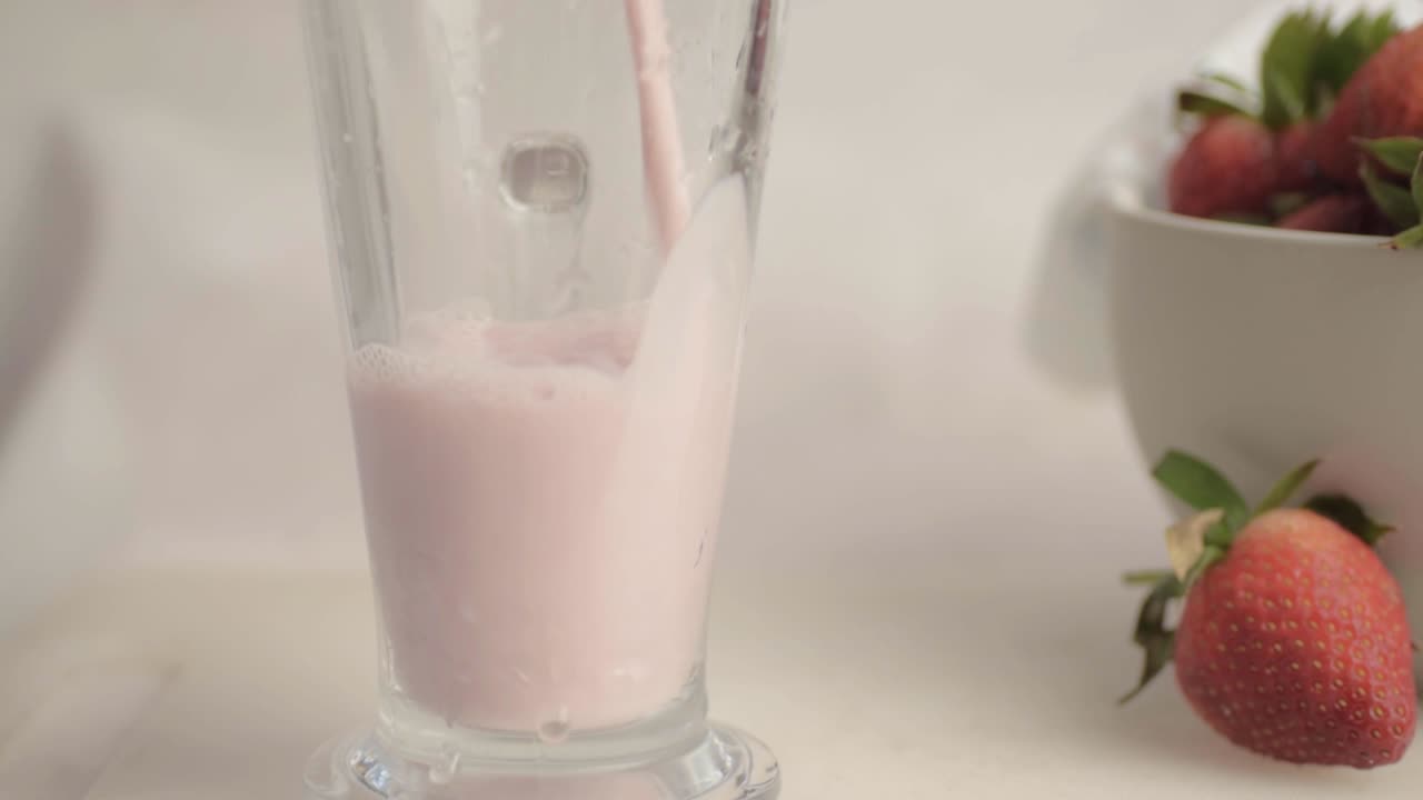 Primer plano medio de un vaso lleno de un batido de fresa recién hecho y espumoso