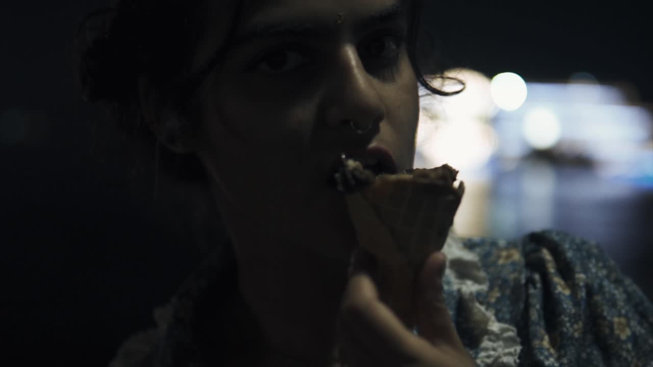 소녀는 밤에 슬로우 모션으로 아이스크림을 먹습니다.