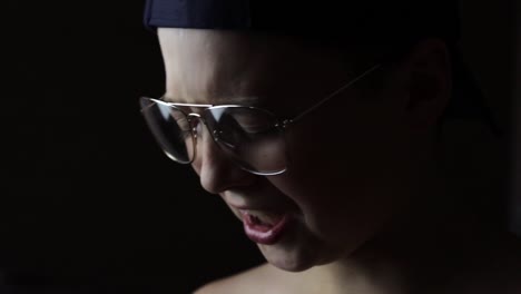 young boy wearing glasses starts crying, isolated on black background