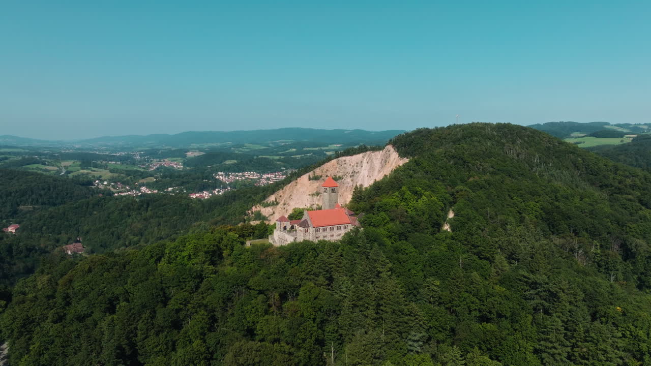 Aerial drone approaches St. Bartholomew Church atop Dilsberg hill, revealing the green valley near Heidelberg, Germany