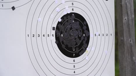 bullets punching through shooting target close up - static clip seeing bullet holes penetrating black and white shooting target