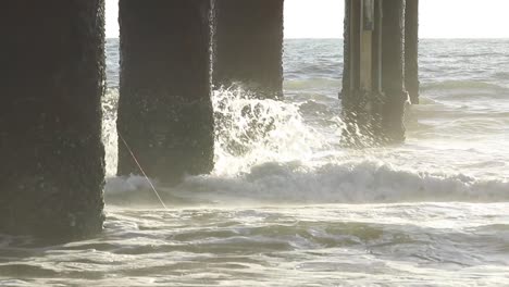 dramatic waves crashing into a pier piling