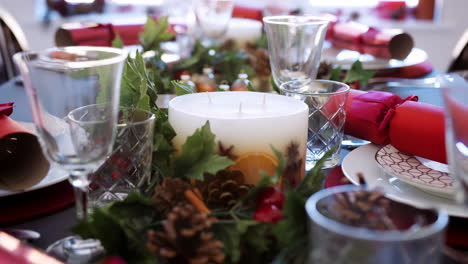 Tiro-Inclinado-De-Una-Vela-Blanca-Sobre-Una-Mesa-De-Comedor-Decorada-En-Preparación-Para-La-Cena-De-Navidad,-Detalle,-Enfoque-Selectivo