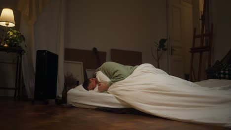 man sleeping on the floor in a messy room