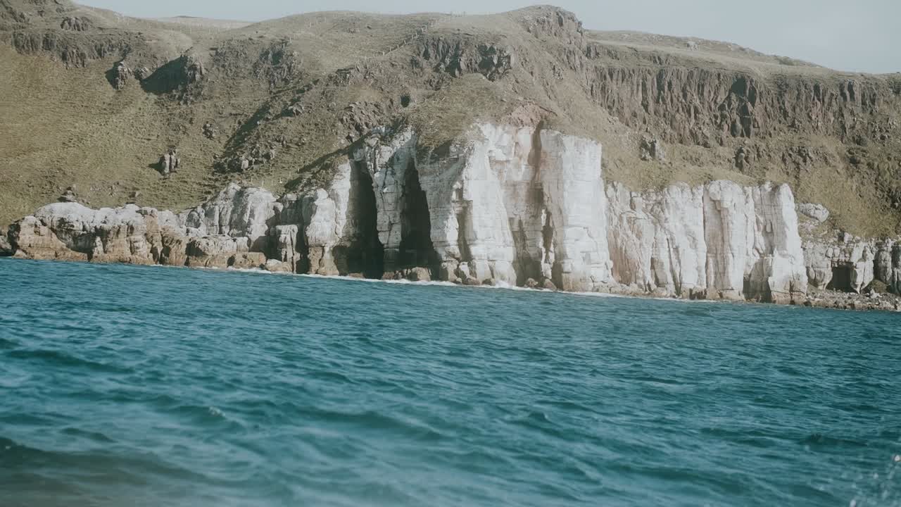 View from boat looking at seaside cliffs, slow motion