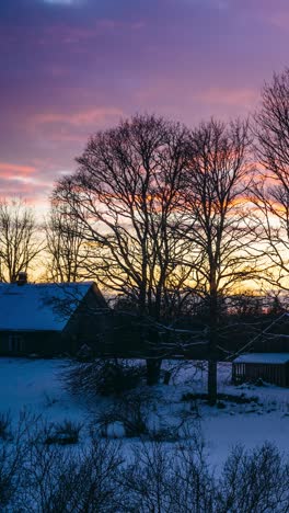 house in the suburbs on a beautiful winter sunset. vertical timelapse of colorful winter sunset over snowy cabin in peaceful countryside landscape.